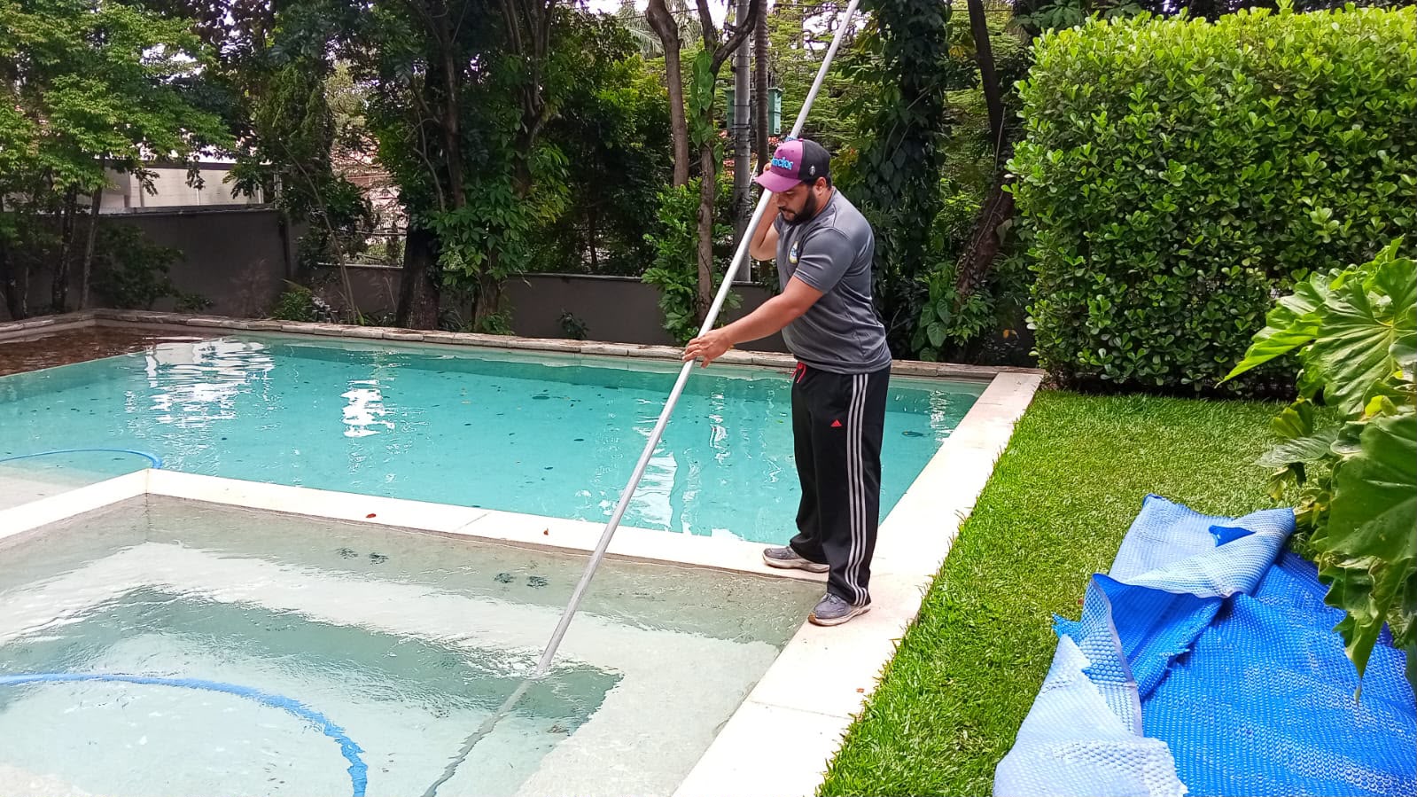 Técnico da Dw Piscinas aspirando uma piscina residencial