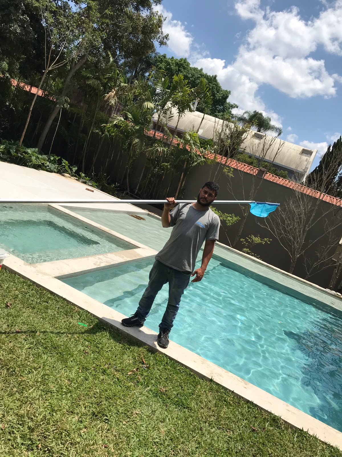 Técnico com peneira em piscina de jardim